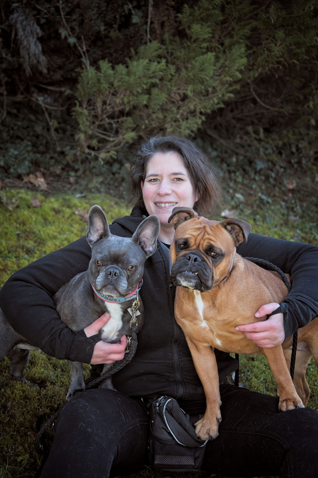 Daniela Marx sitzt im Gras, die Arme um ihre beiden Hunde gelegt