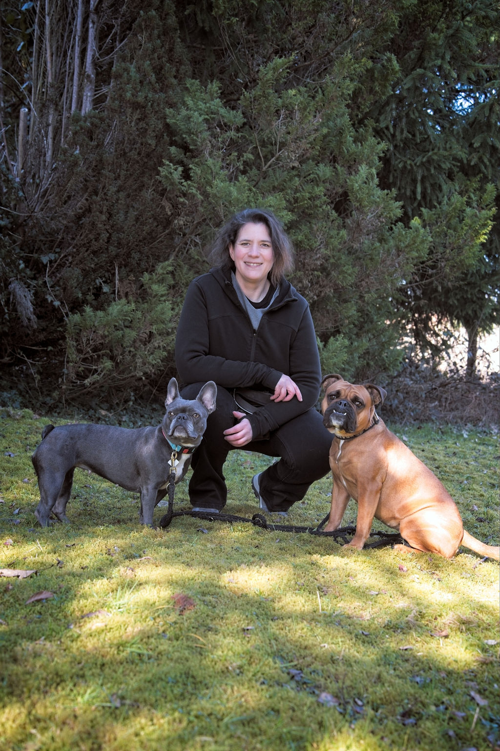 Daniela Marx kniet auf einer Wiese zwischen ihren beiden Hunden